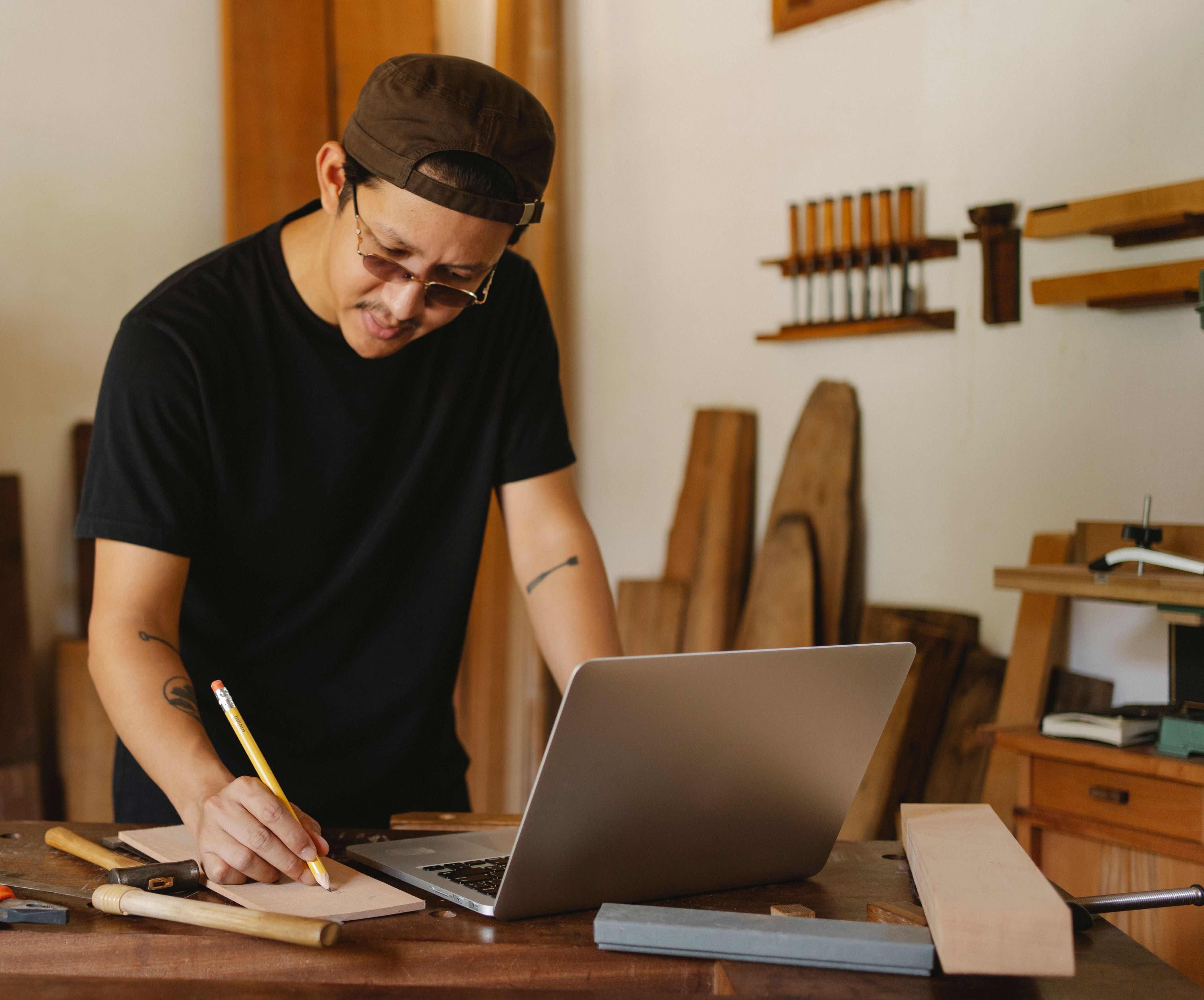 A business owner reviewing notes and a website at a workshop desk